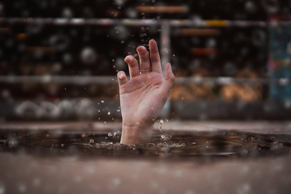 What Helped When Nothing Else Did: A single hand emerges from water, symbolizing a cry for help amidst a rainy setting.